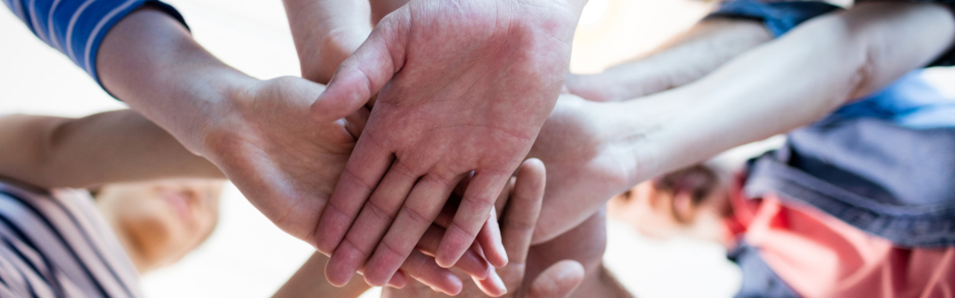 Team legt gemeinsam die Hände übereinander als Symbol für Zusammenhalt.
